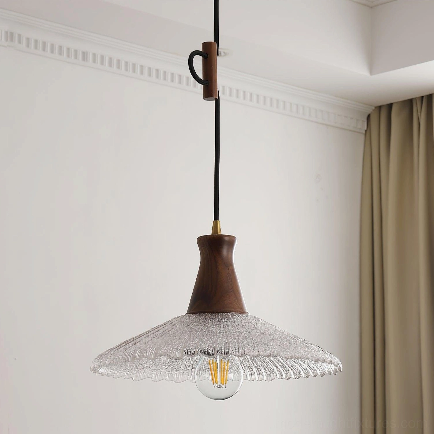 Adjustable height walnut wood pendant light with amber filament bulb, low angle installation view