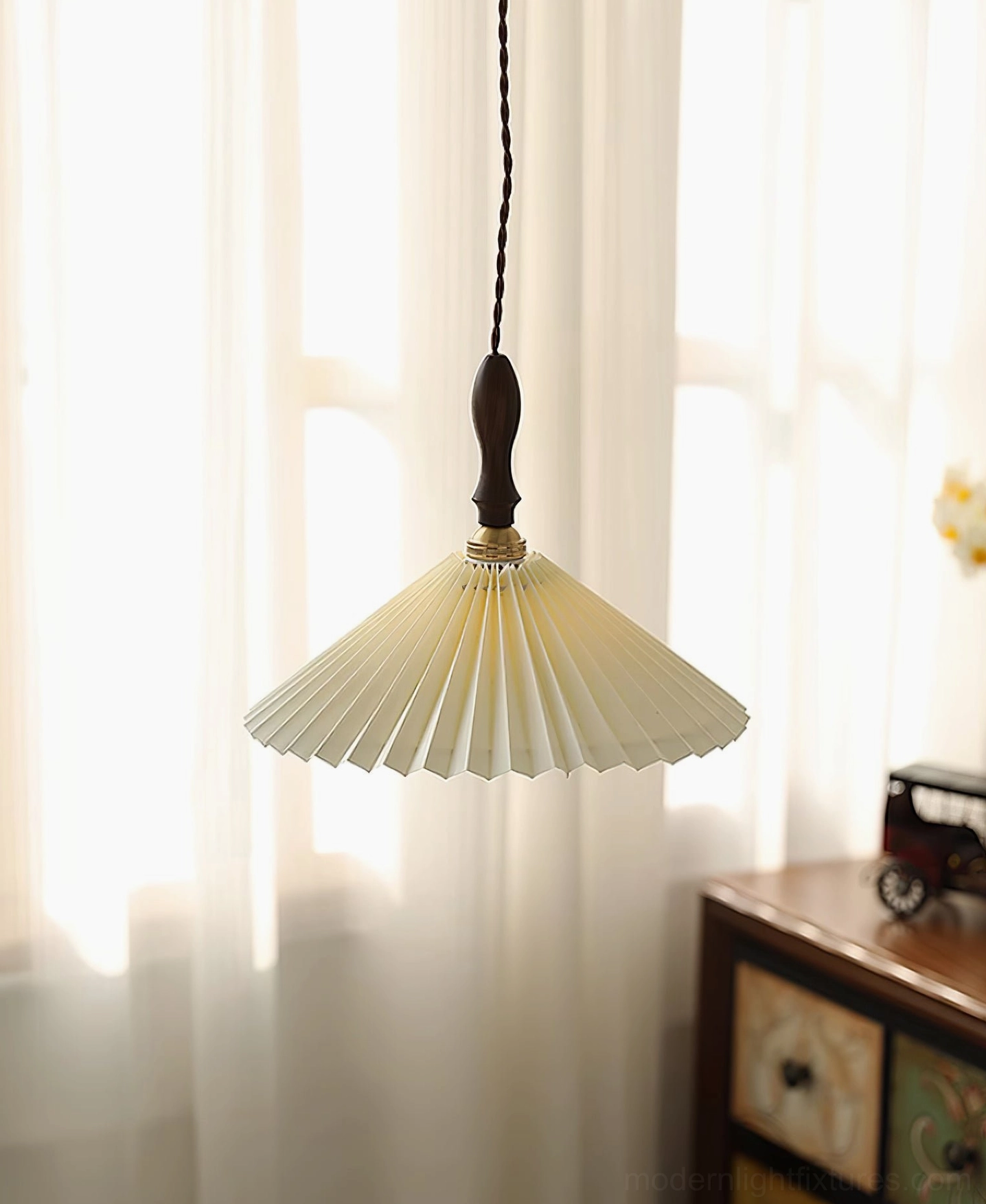 Walnut pleated pendant lamp showing light diffusion through conical fabric shade design