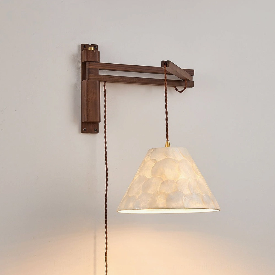 Walnut swing-arm sconce front view with warm back lighting, Capiz shell shade and walnut wood bracket