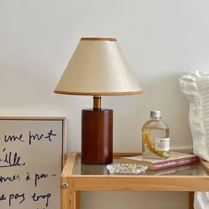 Cylindrical fabric table lamp displayed on side table with books and decorative accessories, warm home interior setting