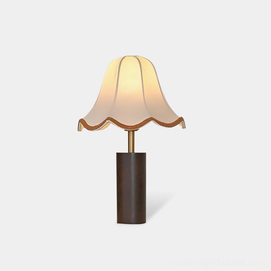 Walnut wood table lamp with scalloped off-white fabric shade and brass trim on white background studio shot