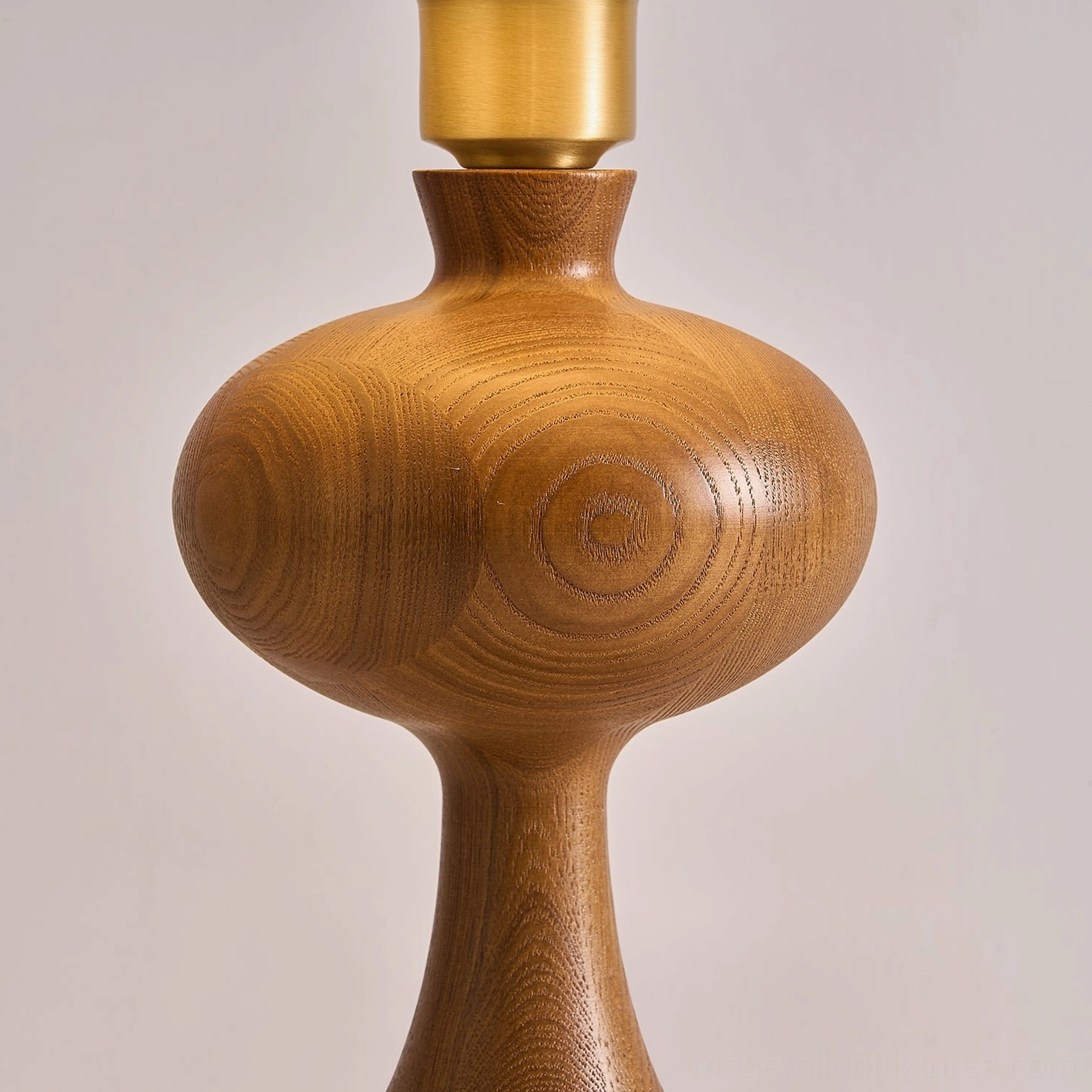 Close-up of carved walnut wood lamp base showing natural grain patterns, turned details, and brass connecting joint