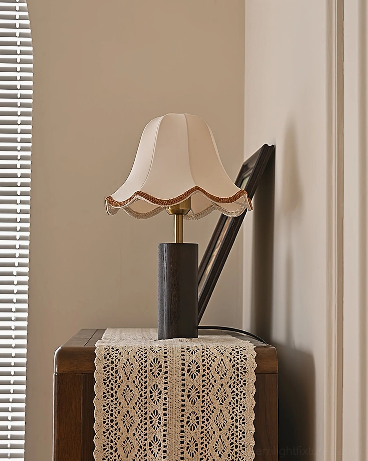 Unlit walnut wood table lamp with scalloped shade on bedroom side table with decorative lace runner