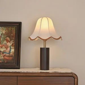 Lit walnut wood table lamp on bedroom dresser with vintage framed art and warm ambient lighting