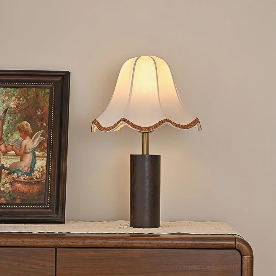 Lit walnut wood table lamp on bedroom dresser with vintage framed art and warm ambient lighting