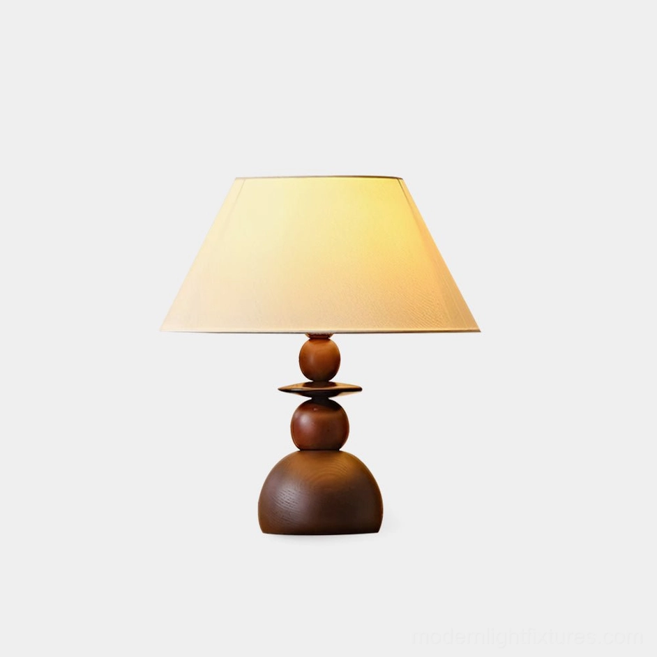 Walnut wood table lamp with beige fabric shade on white background, showing stacked wooden base and clean modern design