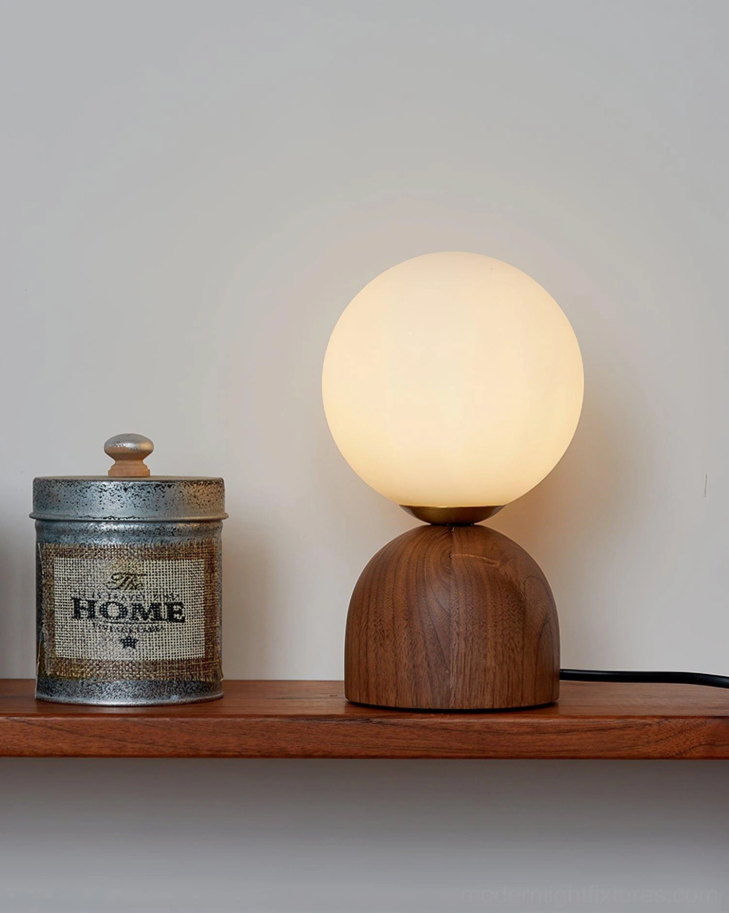 Modern walnut wood table lamp on wooden shelf with vintage metal jar, minimalist home decor