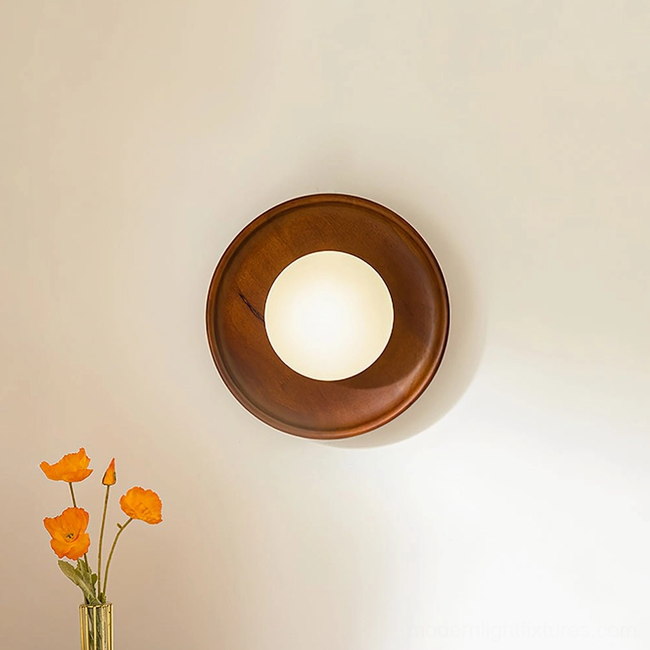 Dark walnut wood wall sconce with frosted glass shade installed in modern bedroom setting