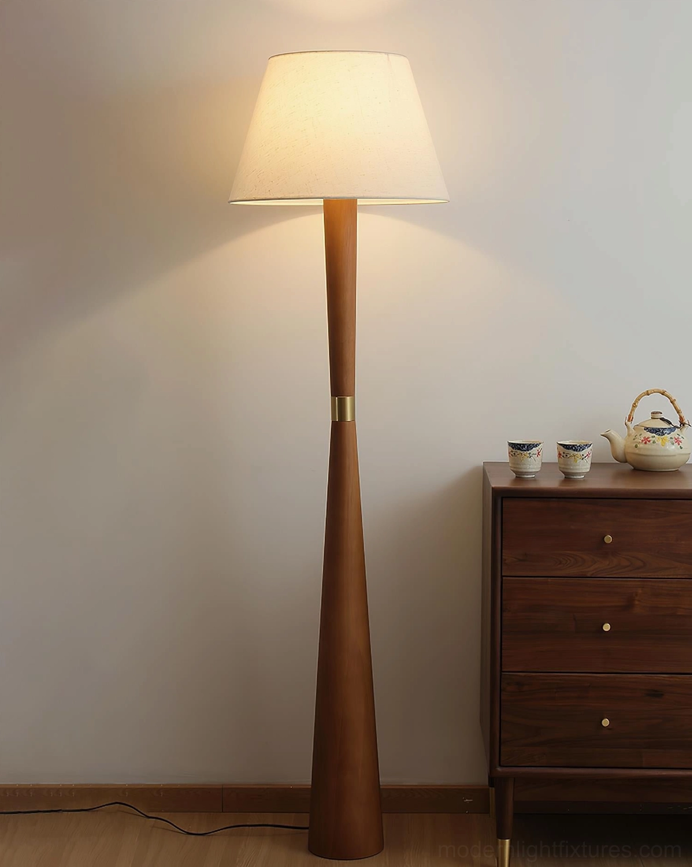 Contemporary minimalist floor lamp with tapered wood body illuminated in cozy living space with wooden furniture