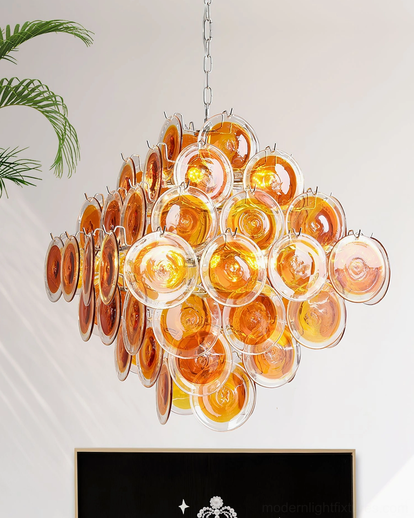 Warm amber tone hand-blown glass disc chandelier front view in luxury living room with fireplace feature and full glass cluster