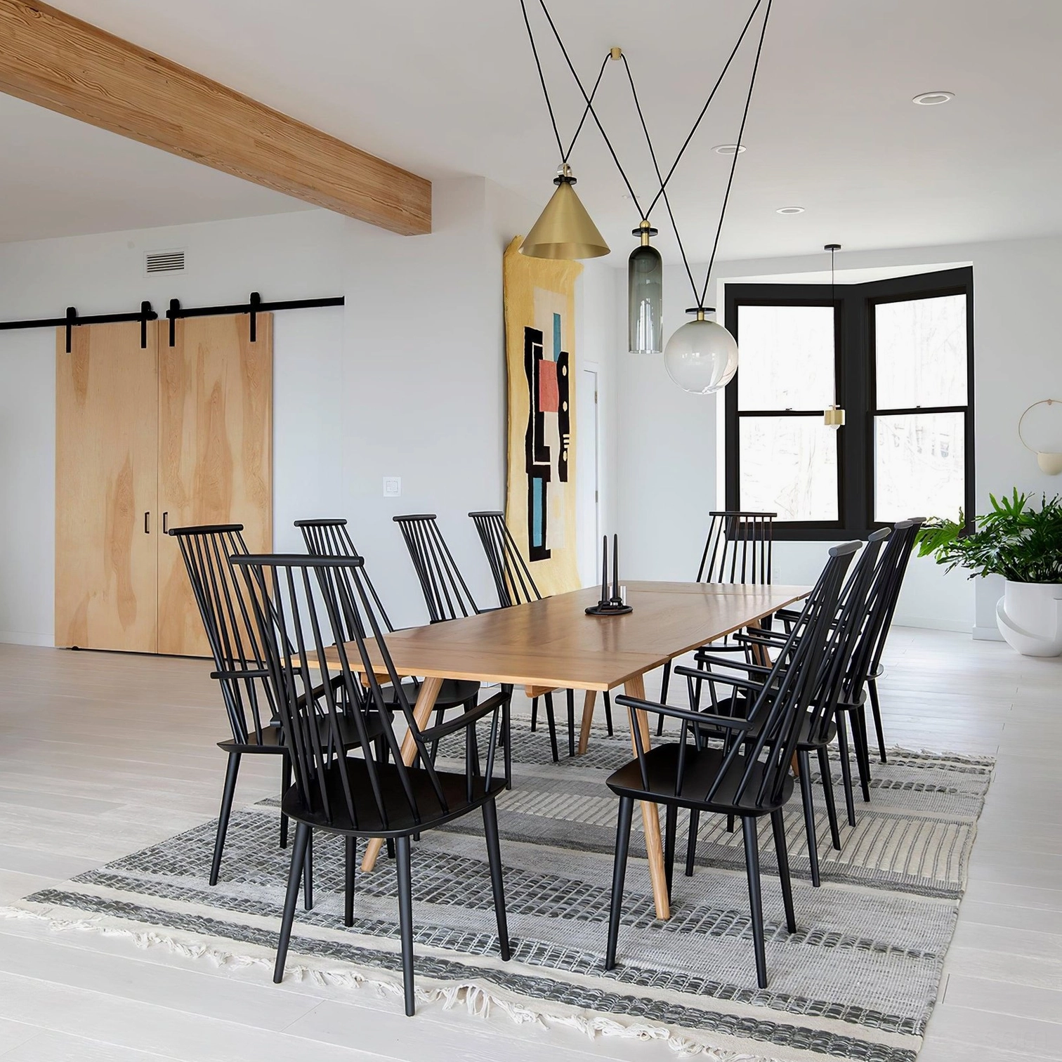 Asymmetrical geometric pendant light cluster in warm metal tones above modern wooden dining table
