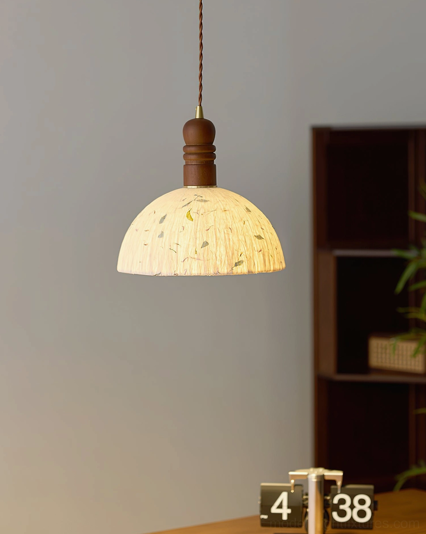 Warm yellow rice paper dome pendant lamp against wooden display shelf, wabi-sabi home decor