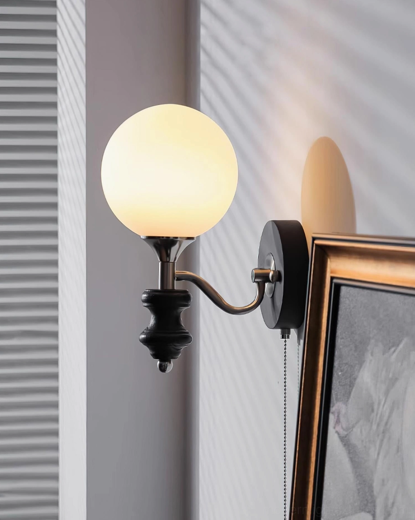 Warm-toned glass globe wall sconce mounted on interior wall with framed artwork