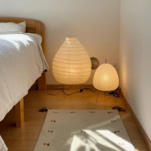 Two washi paper table lamps of different sizes in wooden bedroom corner with warm ambient lighting