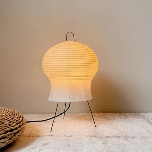 Minimalist paper shade table lamp lit with warm glow in cozy living room setting with area rug