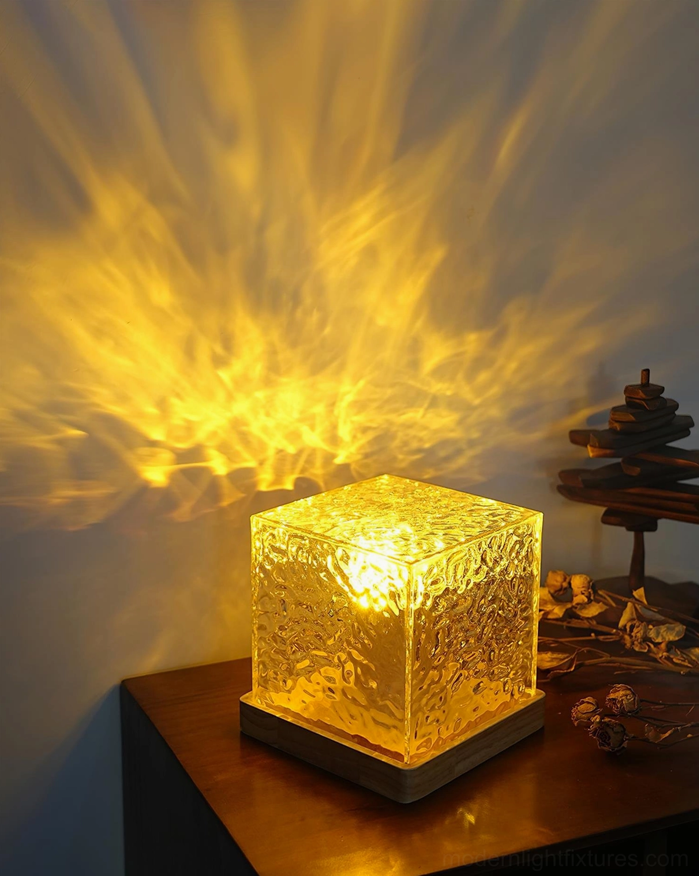 Warm yellow water ripple table lamp on wooden side table with decorative objects, casting amber ripple shadow pattern