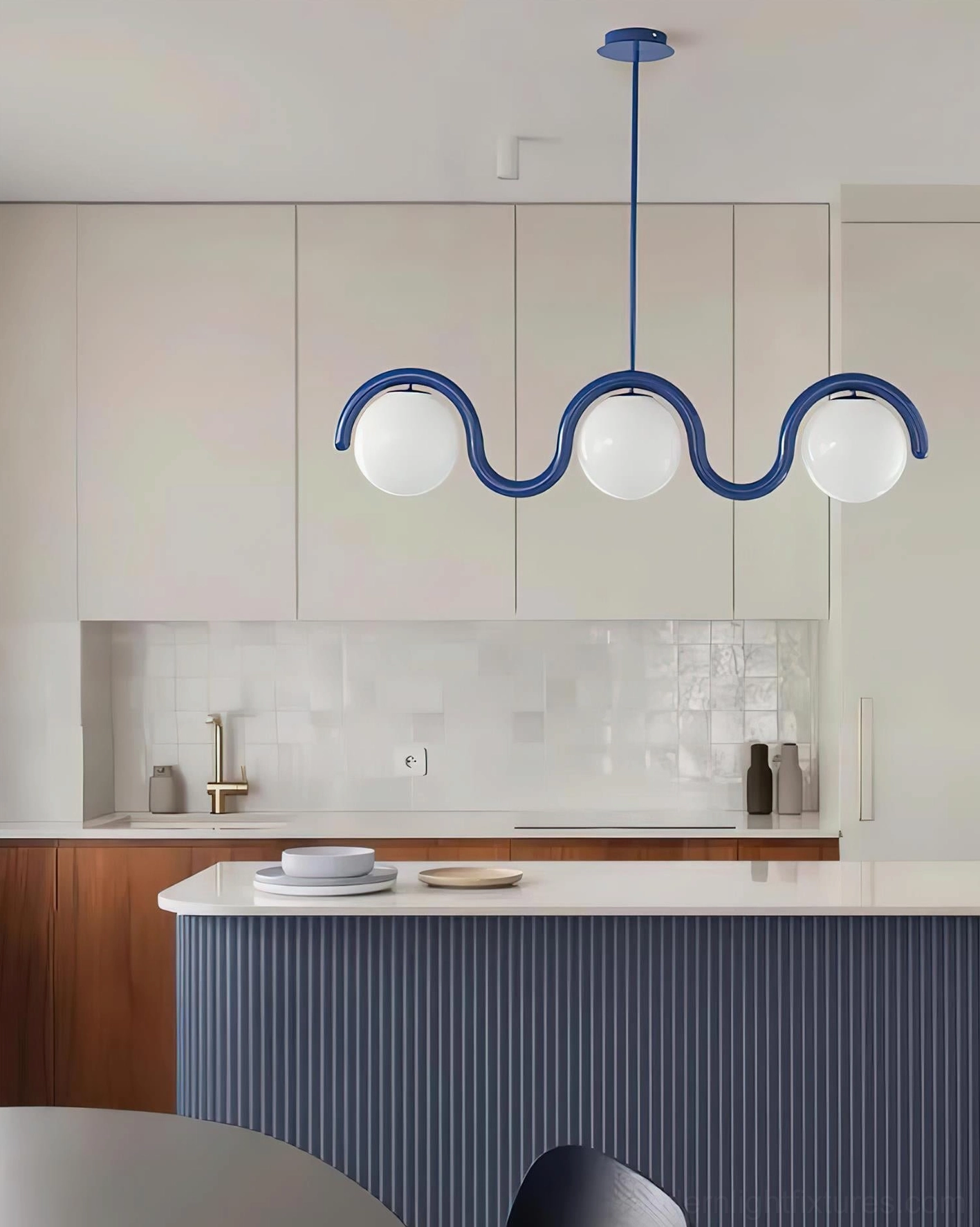 Contemporary kitchen interior with 3-light blue frame wave chandelier above island counter