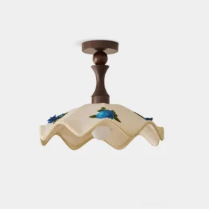 Front low-angle view of wavy scalloped ceiling lamp with hand-embroidered floral details and pastoral fabric shade against white studio background