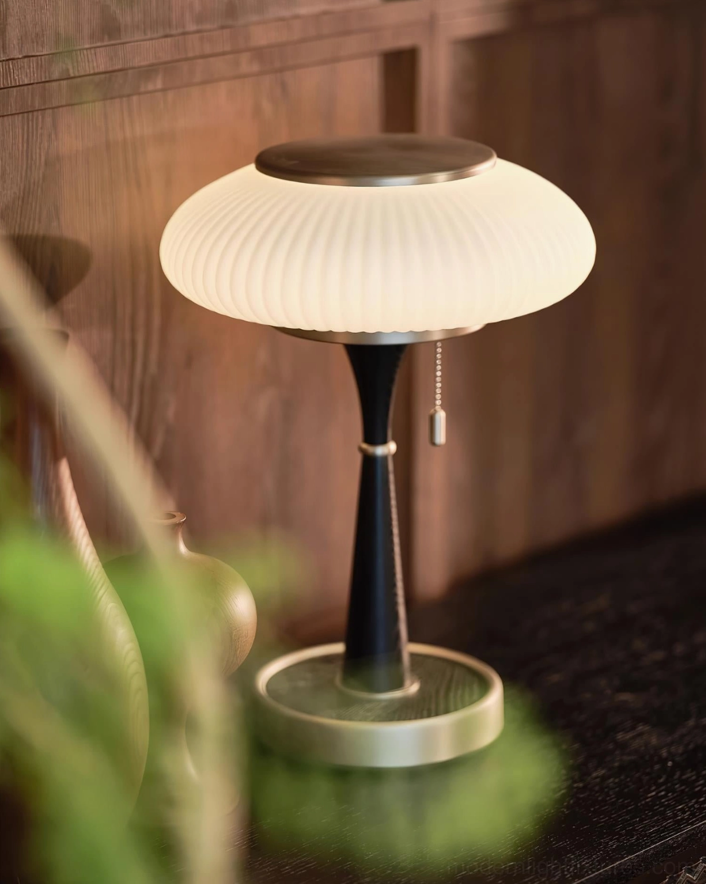Close-up detail of Welma pleated table lamp showing black metal pole silver base white ribbed shade with pull chain switch on wooden sideboard