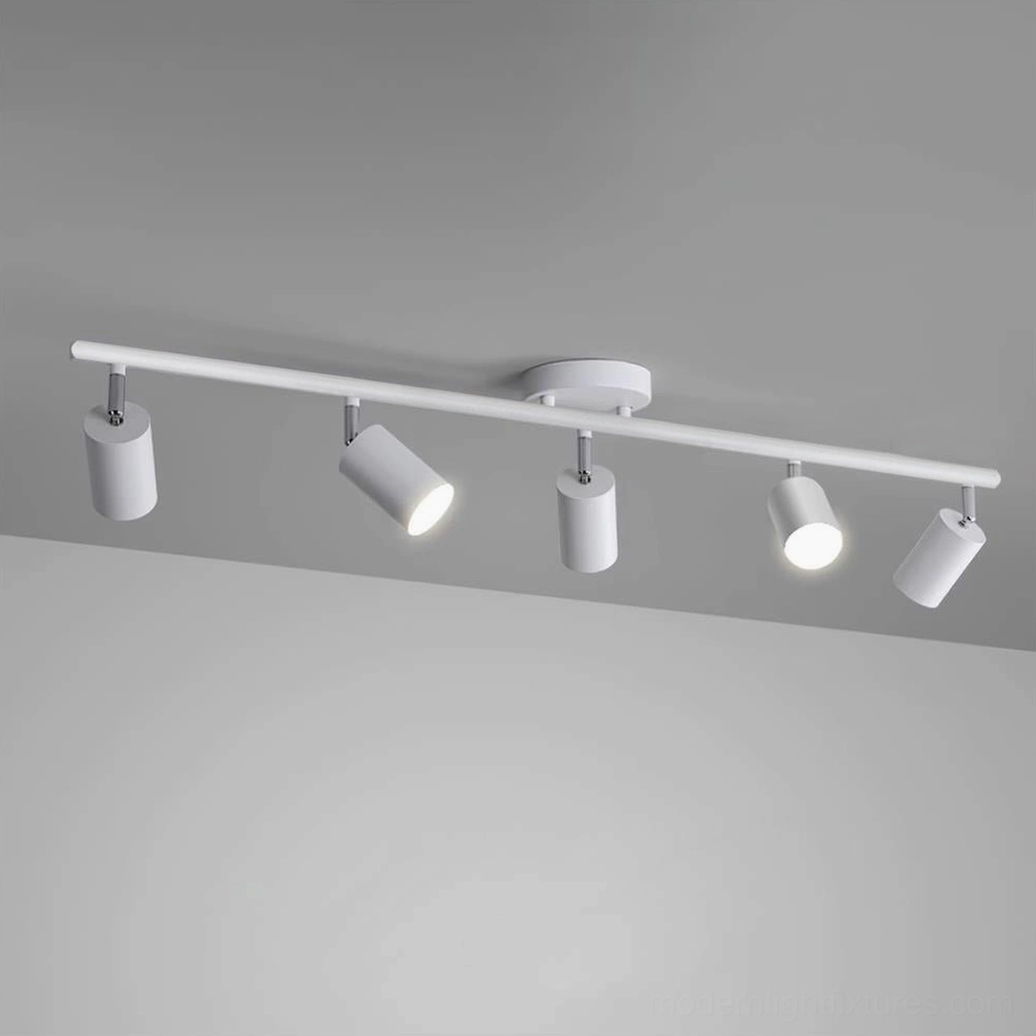White 5-head adjustable track lighting fixture mounted on ceiling, showing multiple illuminated spotlights