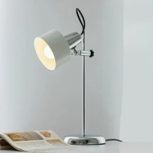 White adjustable desk lamp with polished chrome frame and metal shade, three-quarter view on magazine table setting