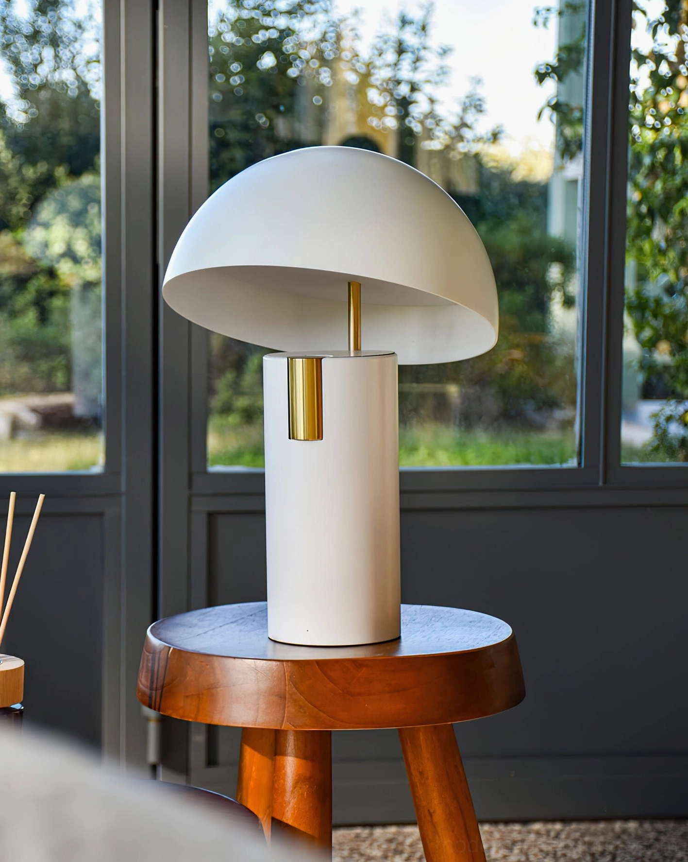 White Avo mushroom LED table lamp with matte finish and brass decorative accent, side angle in natural window light