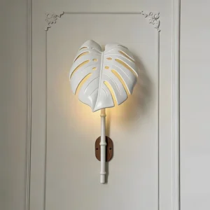 White botanical wall lamp illuminated on studio paneled wall displaying warm light glow