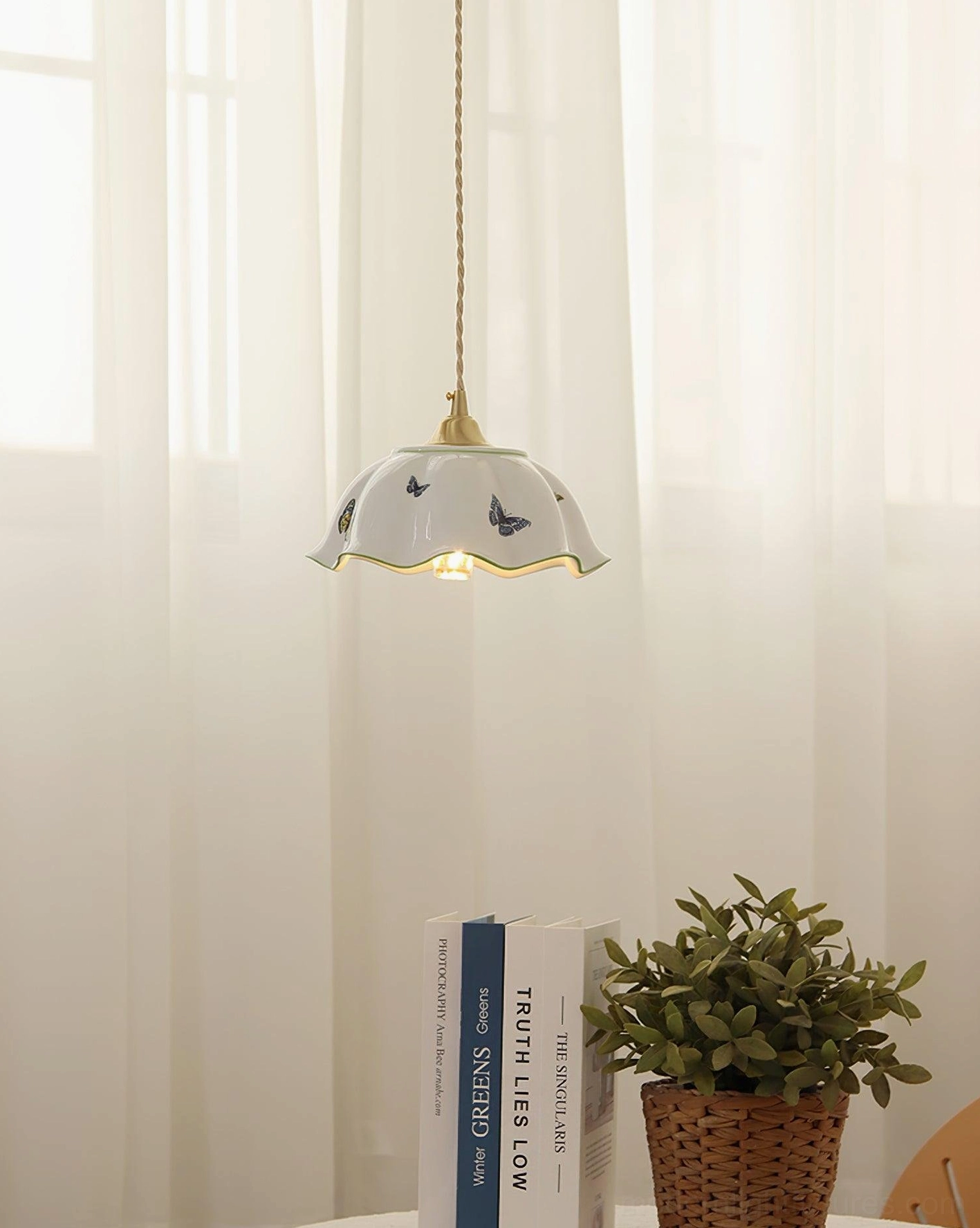 White ceramic pendant lamp with butterfly design near window in cozy bedroom study nook