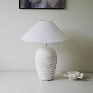 Modern white ceramic table lamp styled in minimalist interior with ceramic flower decor and wall art