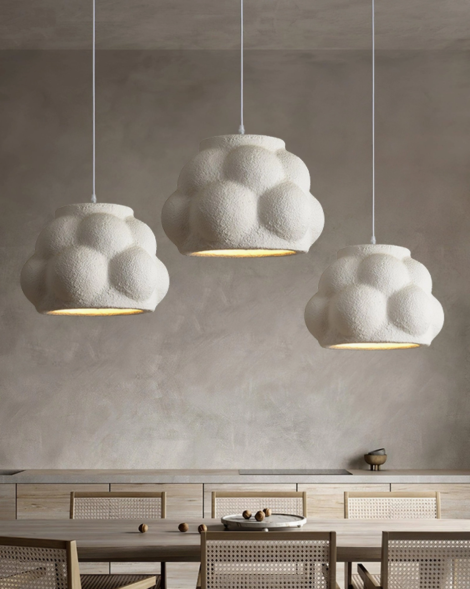 Three white warm-glowing cloud pendant lamps in minimalist modern dining space