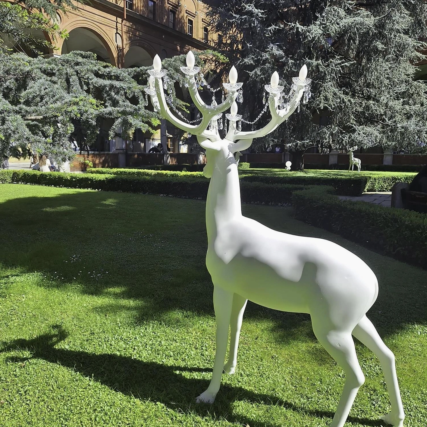 White deer sculpture lamp with crystal chandelier antlers in natural outdoor lawn setting