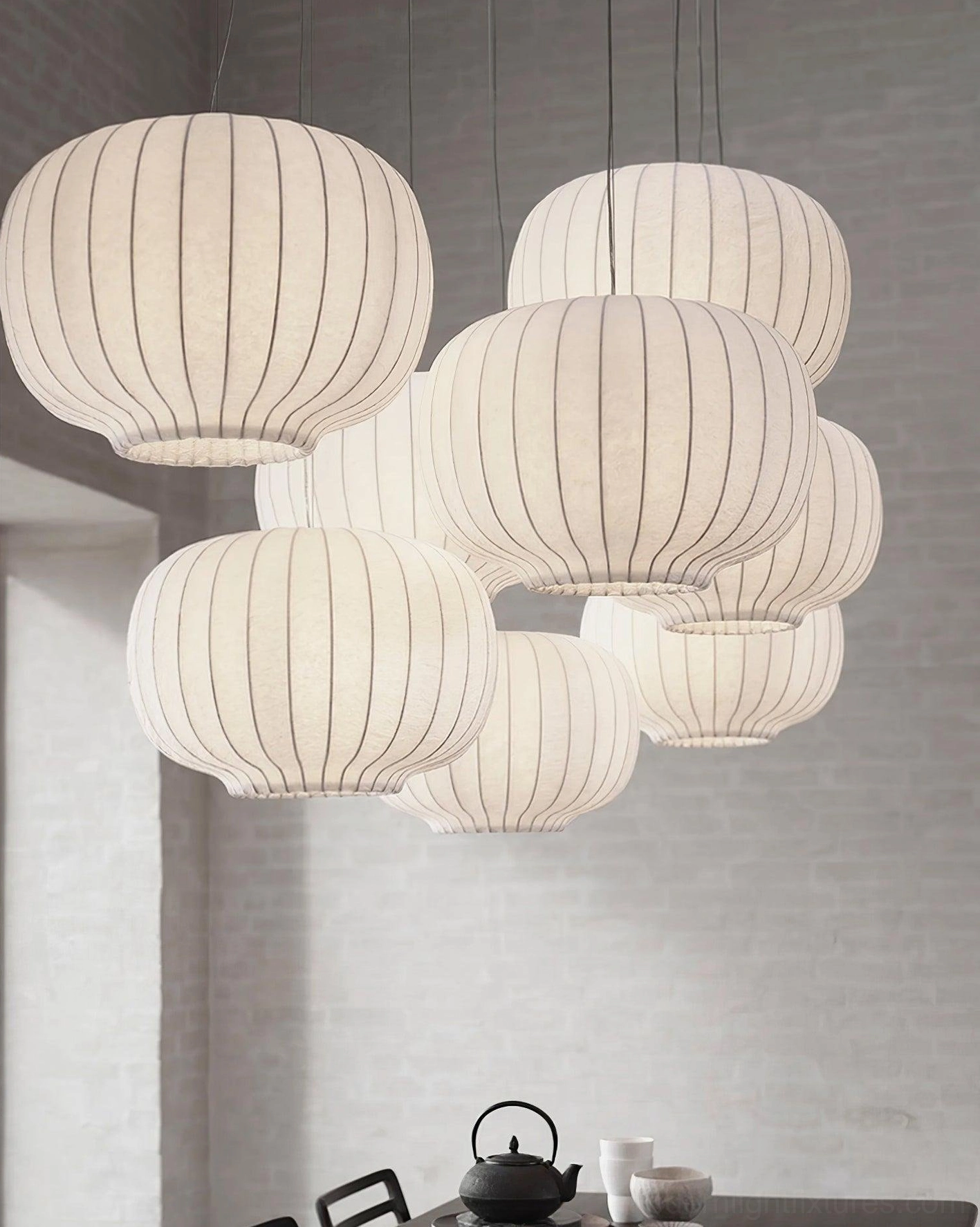 Multiple off-white fabric pendant lights with ribbed texture in minimalist dining space