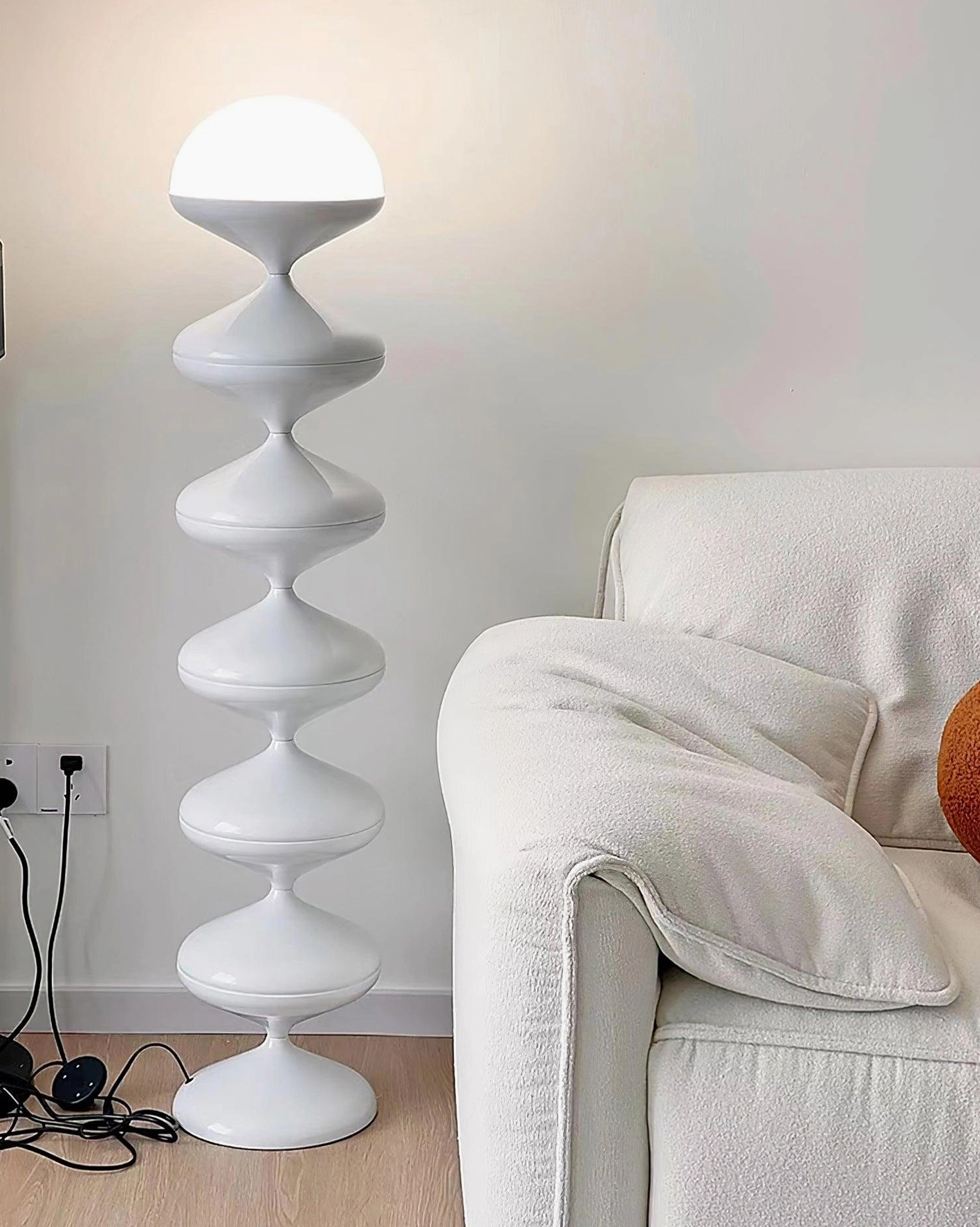 White matte gourd floor lamp in cream colored minimalist bedroom with soft furnishings