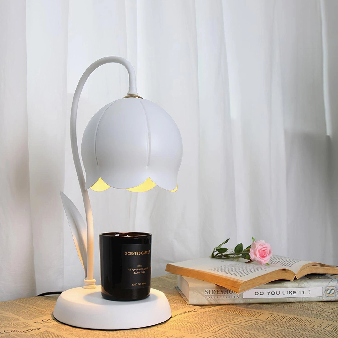 White lily flower candle warmer lamp three-quarter view on home desk with books and pink flower decor