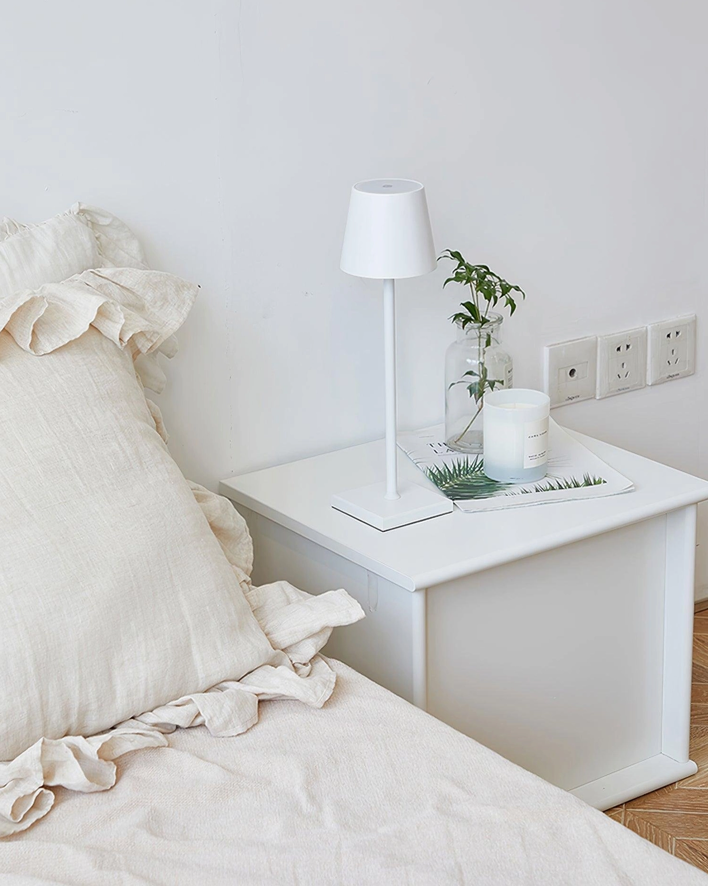 Contemporary white minimalist table lamp with fabric tapered shade in cozy Nordic style bedroom setting