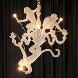 White monkey chandelier with glowing warm light bulbs centered front view on dark curtain background