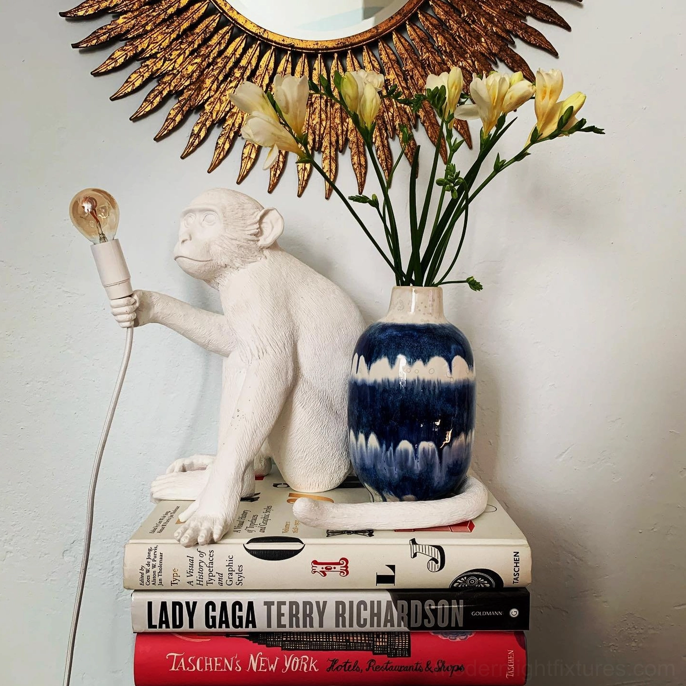 White monkey table lamp kneeling pose three-quarter view on coffee table books