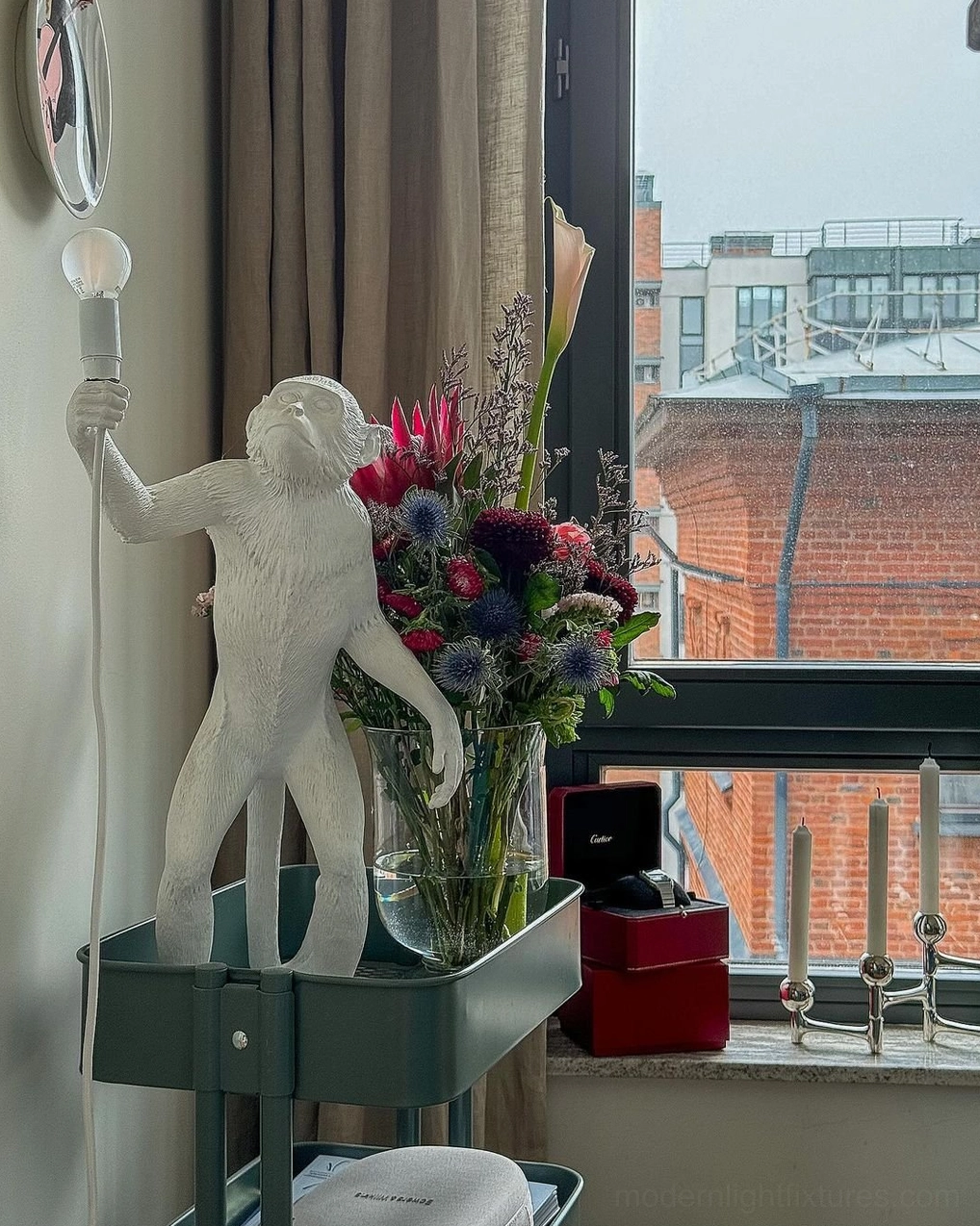 White monkey table lamp three-quarter side view on green metal side table by window
