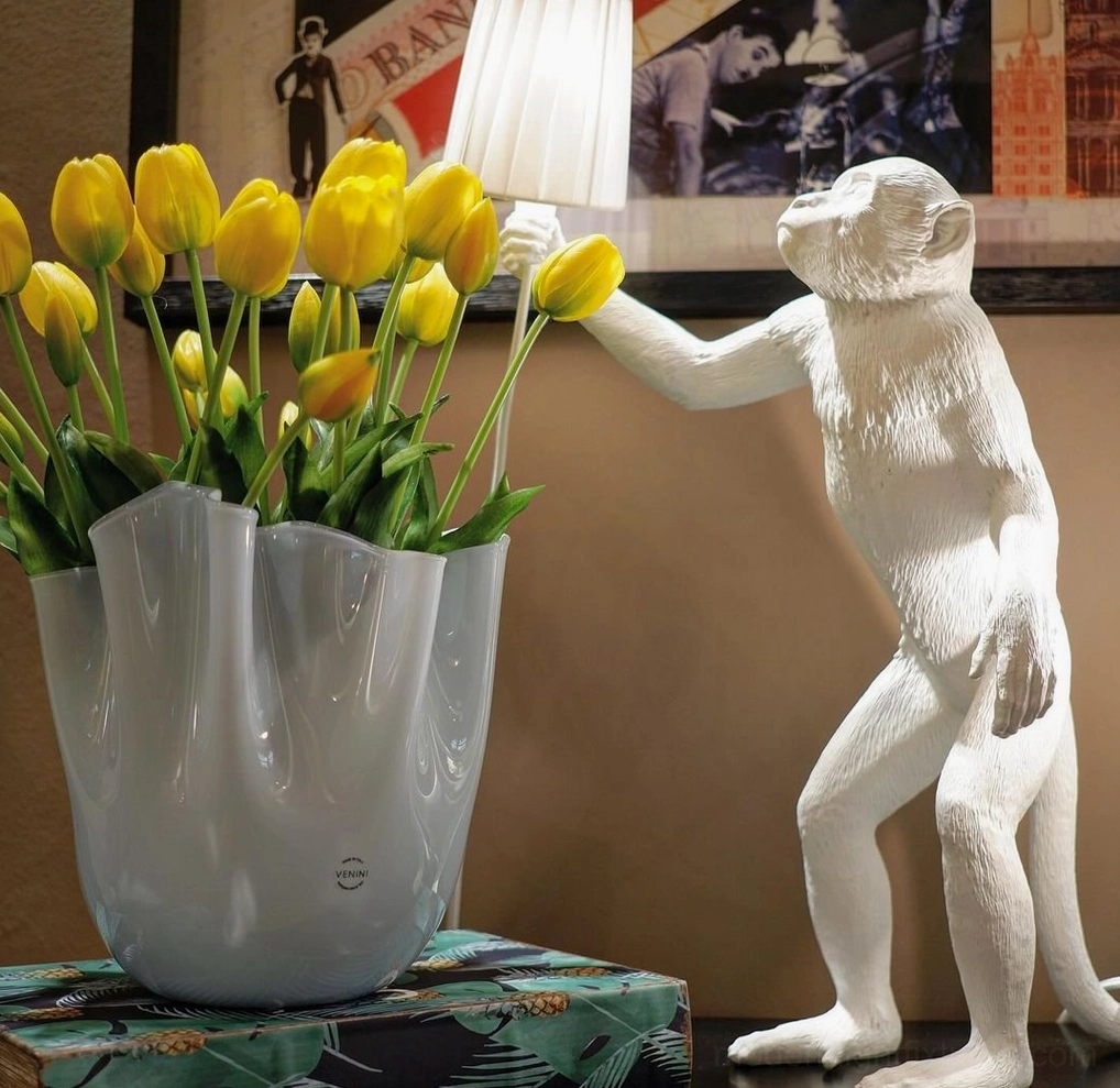 White monkey table lamp standing pose side profile with yellow tulip vase in living room