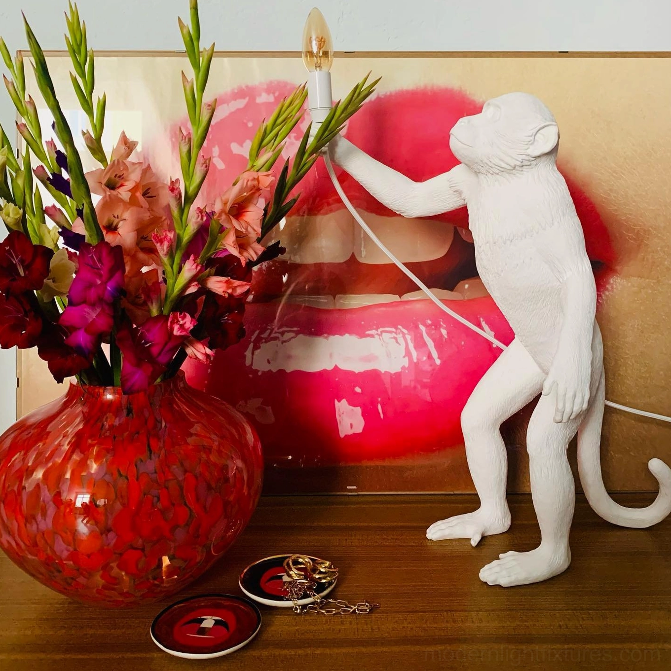 White monkey table lamp standing design side profile reaching for bulb in pop art room