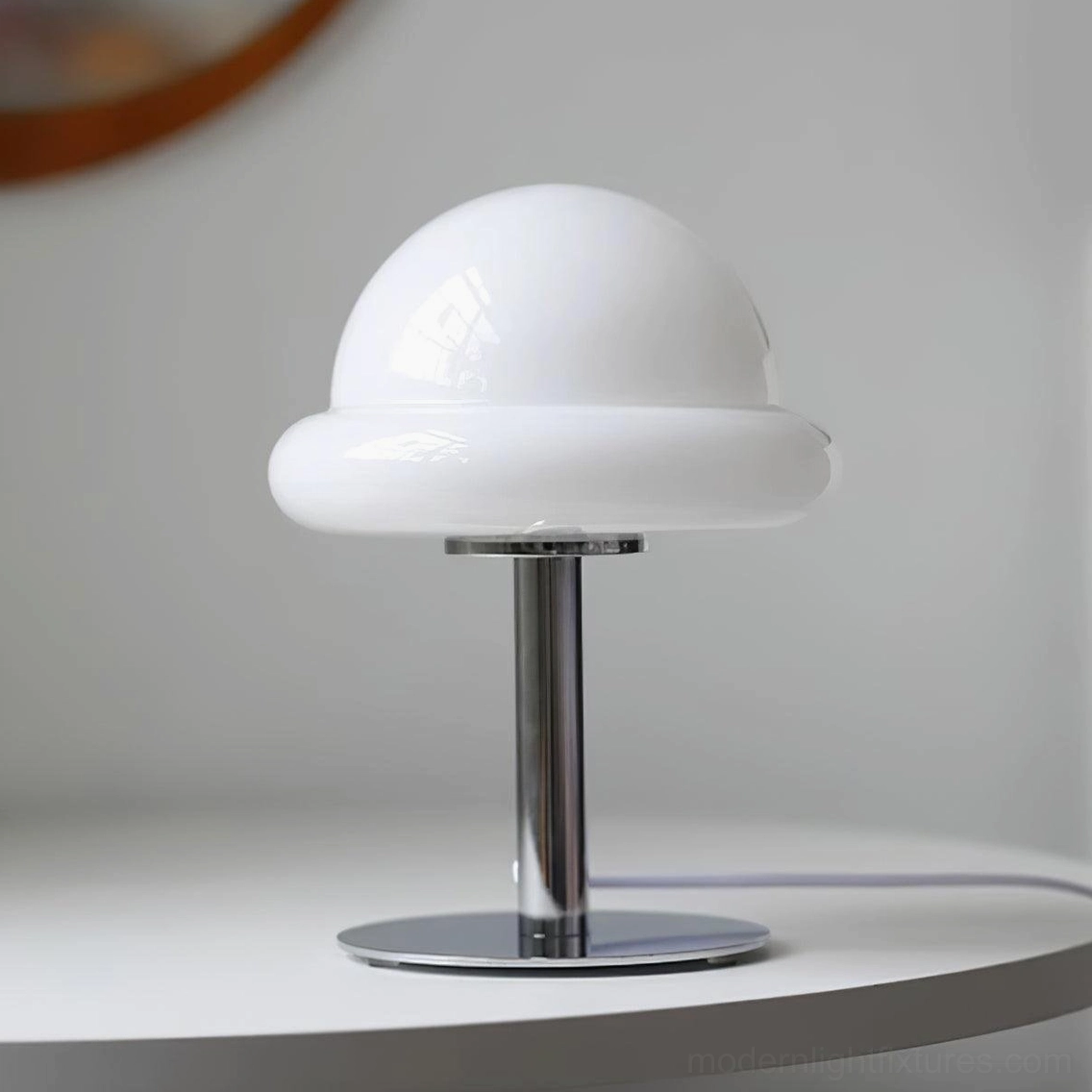White glossy glass mushroom table lamp on white circular side table with polished chrome stand