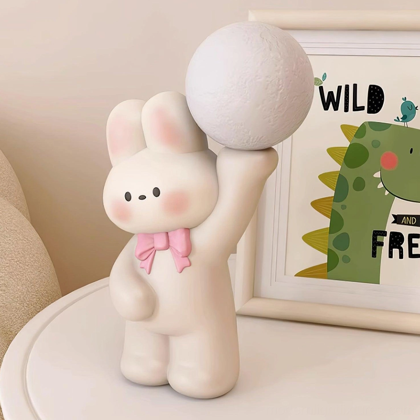 White rabbit moon lamp on side table next to children's artwork - modern nursery lighting solution