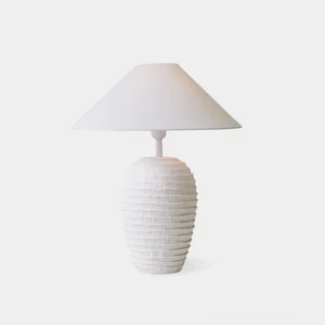 White ribbed ceramic table lamp with sculptural textured base and fabric cone shade, front view on studio background