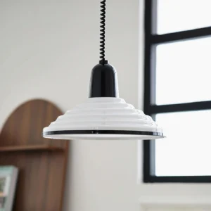White ribbed pendant light hanging in minimalist residential interior with black-framed window, mid-century modern style