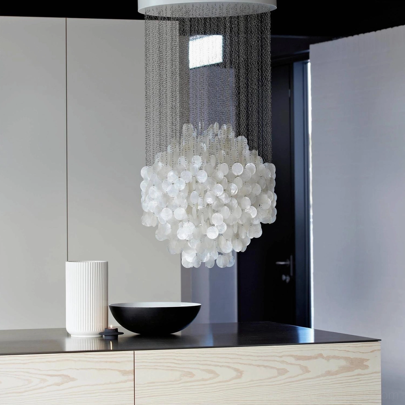 Modern white shell chandelier hanging in minimalist hallway with pure capiz shells and metal suspension chains