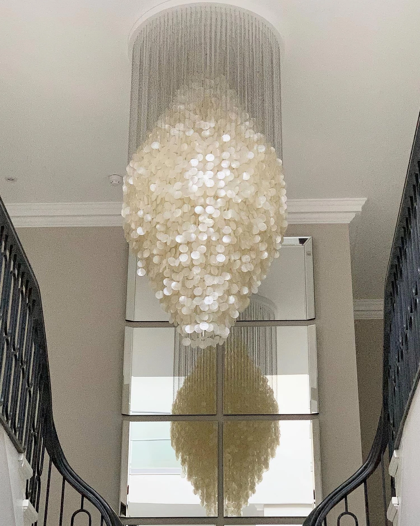 White metal frame shell chandelier with cascading capiz shells creating sculptural focal point in home