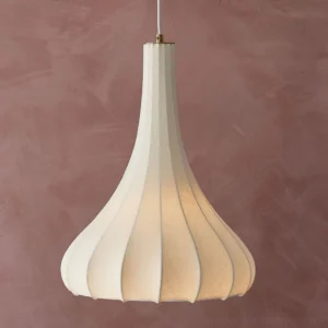 Modern white fabric pendant lamp hanging against dusty rose wall, brass ceiling fixture detail with warm lighting