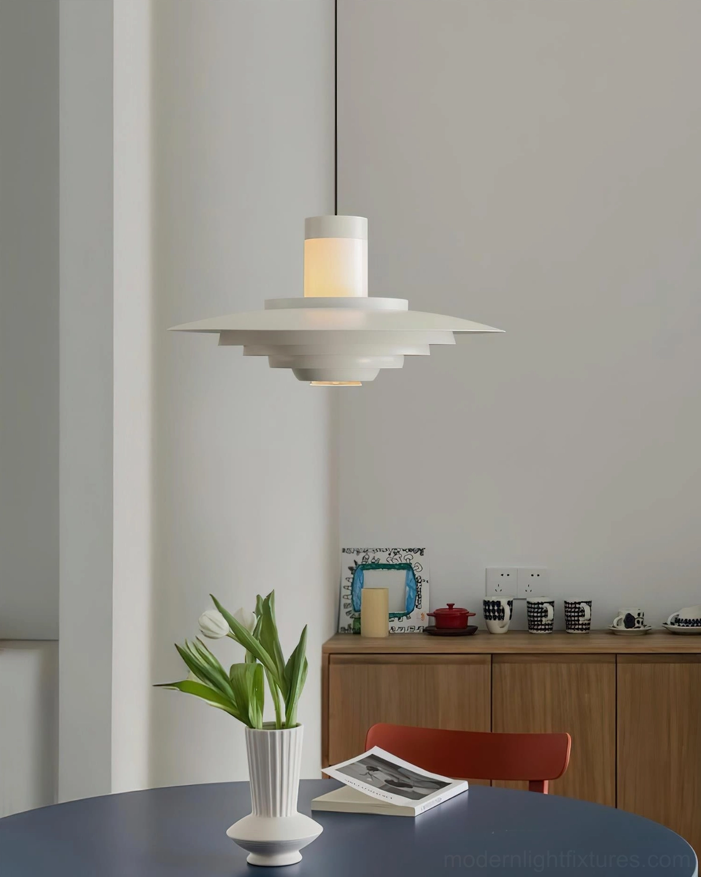 Pure white matte tiered pendant light creating dramatic shadows in modern Nordic minimalist home dining area with contemporary interior design