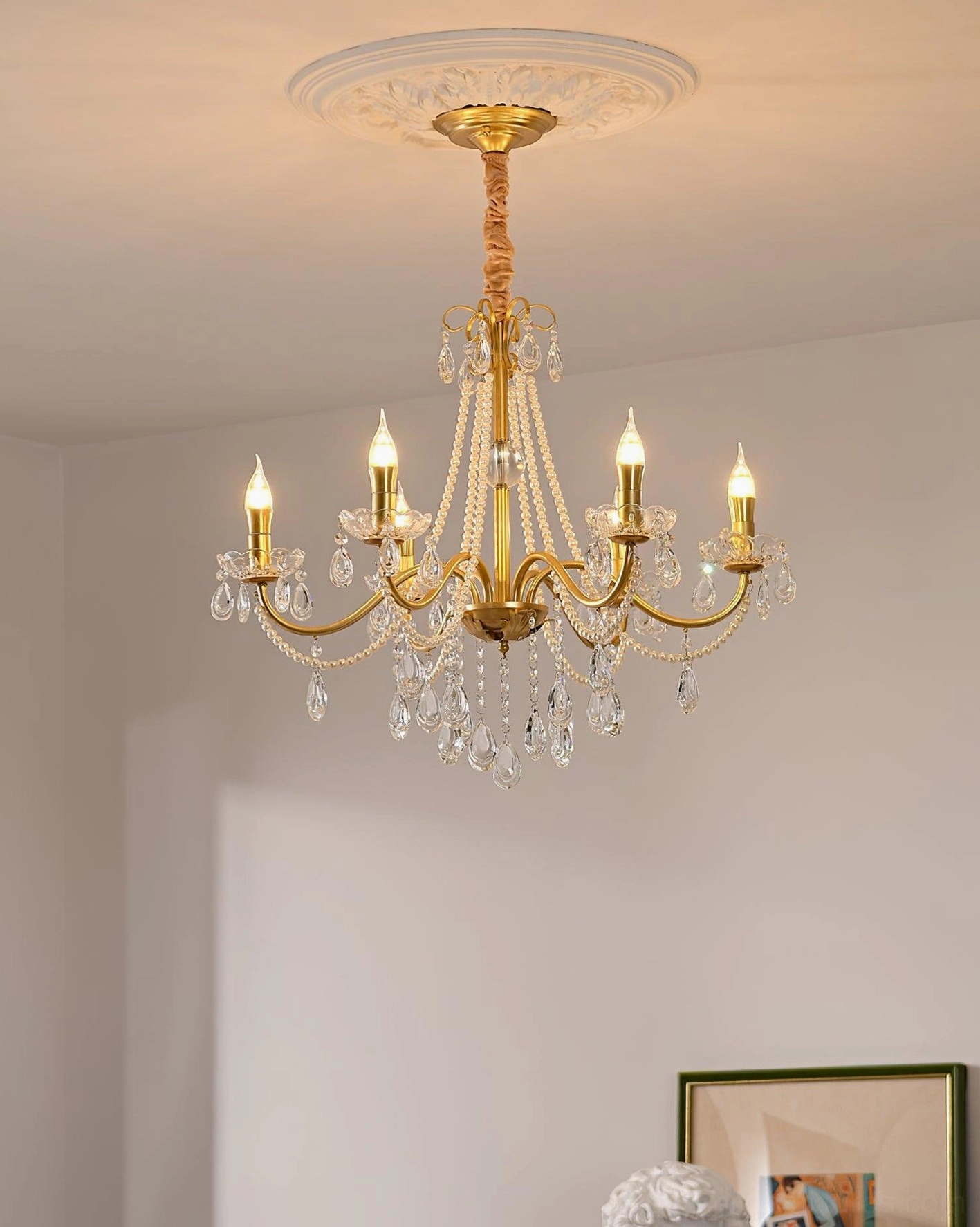 Crystal chandelier mounted on ornate ceiling medallion, residential interior installation with warm ambient lighting