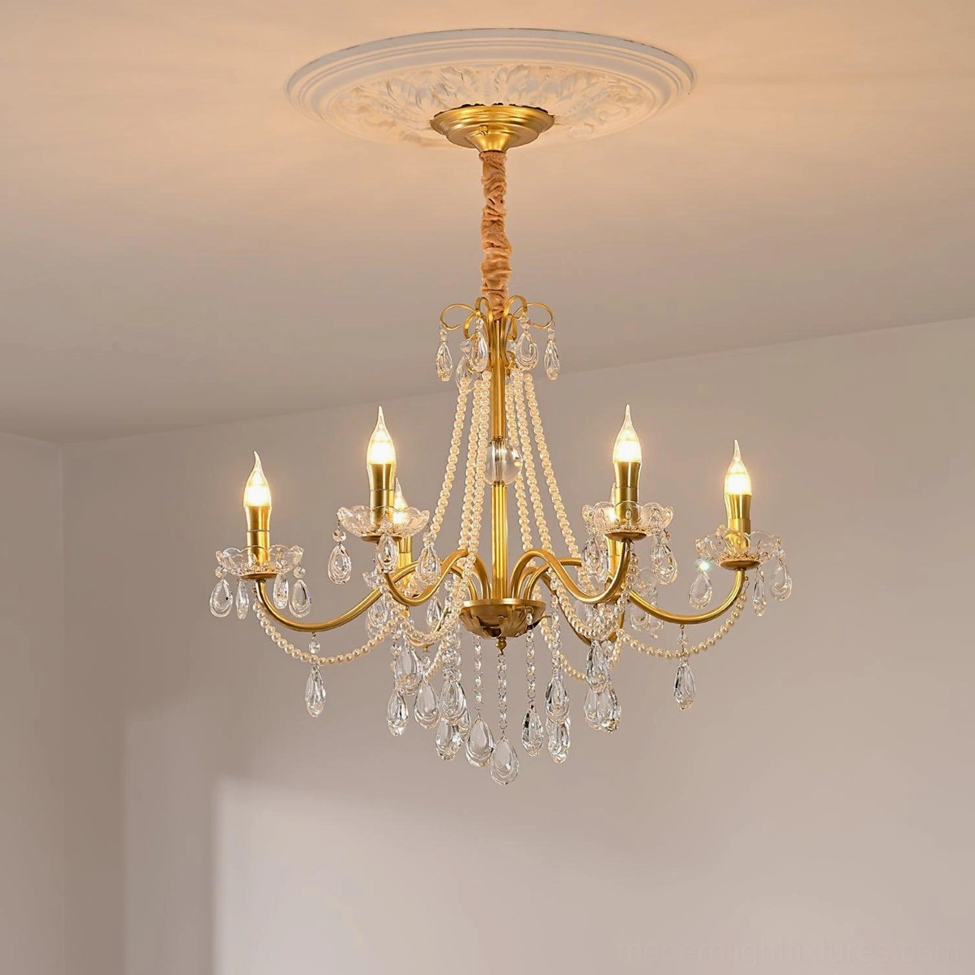 Elegant crystal chandelier installed on decorative ceiling medallion, warm lighting accent in formal dining room